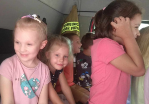 Dzieci siedzą w kabinie wozu strażackiego.
