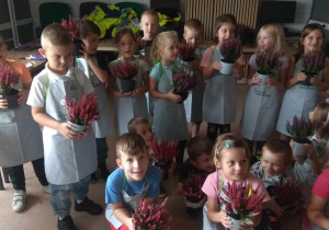 Dzieci pozują do zdjęcia ze swoimi przesadzonymi już roślinkami.