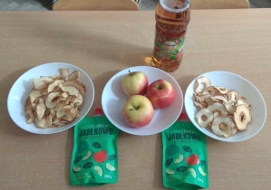 Na stole leżą jabłka w różnych postaciach: surowe, suszone, mus, sok.