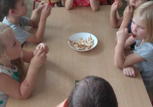 Dzieci smakują suszone jabłka.
