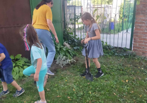 Dzieci wraz zRodzicami sadzą cebulki kwiatowe.