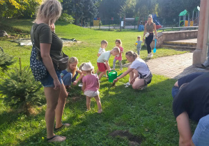 Dzieci wraz zRodzicami sadzą cebulki kwiatowe.