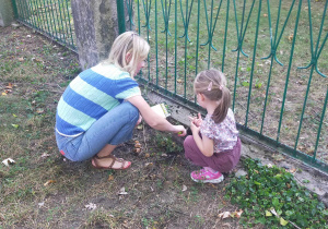 Mama z córką sadzą cebulki kwiatowe.