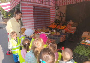 Dzieci stoją przed sklepem owocowo - warzywnym.