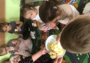 Dzieci czestują się jabłkiem.