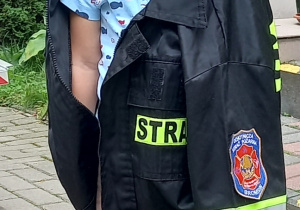 Chłopiec ubrany w elementy stroju strażackiego.