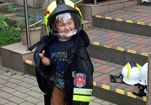 Chłopiec ubrany w elementy struju strażackiego.
