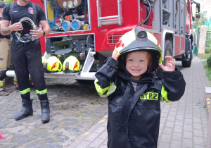 Dziewczynka ubrana w elementy stroju strażackiego.