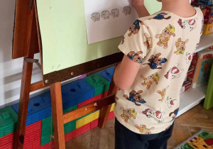 Chłopiec zapisuje wynik matematycznego działania.