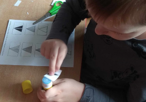 Chłopiec smaruje trójkąt klejem.