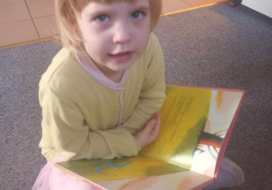 Dziewczynka oglada książkę.