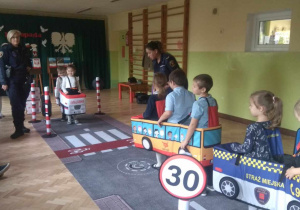 Dzieci w roli pieszych i samochodów uczą się poruszać w ruchu ulicznym.