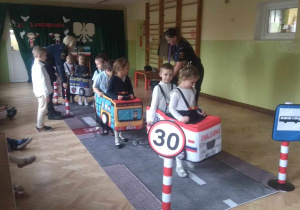 Dzieci w roli pieszych i samochodów uczą się poruszać w ruchu ulicznym.