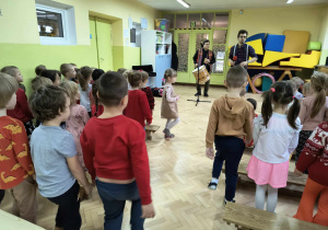 Dzieci tańczą i wykonują odpowiednie kroki do słyszanej piosenki.