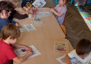 Dzieci kolorują elementy plakatu.