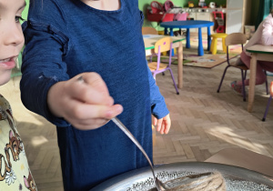 Dziecko przekłada żelowe kulki przy pomocy łyżki do wazonu