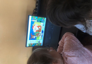 Dzieci kolorują świąteczny obrazek na komputerze.