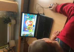 Chłopiec koloruje świąteczny obrazek na komputerze.