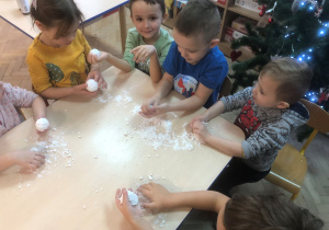 Dzieci lepią kulki ze sztucznego śniegu.