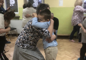 Dzieci wraz z dziadkami przytulają się w tańcu.