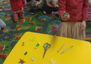 Na stoliku leżą przedmioty z różnego rodzaju materiału: plastiku, drzewa, metalu. Dzieci sprawdzają, co przyciągnie magnes.