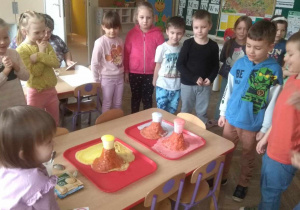 Dzieci obserwują wybuch w makietach wulkanów.