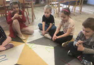 Dzieci układają literę ze sznurka.