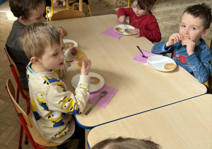 Dzieci jedzą placki przygotowane przez mamę Mateusza i Filipa.