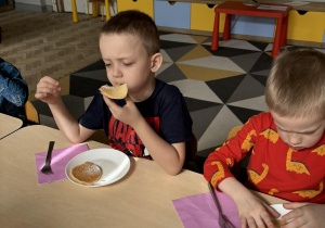 Dzieci jedzą placki przygotowane przez mamę Mateusza i Filipa.