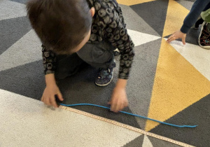 Chłopiec mierzy sznurek.