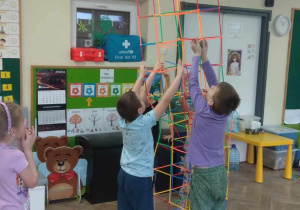Dzieci budują przestrzenną budowlę, która sięga prawie do sufitu.