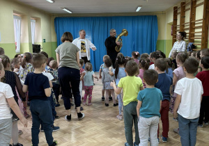 Dzieci słuchają utworu wykonywanego na instrumencie dętym.