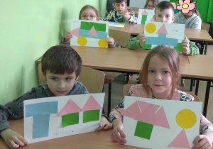 Dzieci prezentują swoje prace, wykonane z figur geometrycznych.