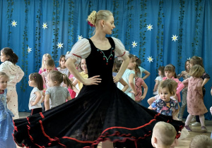 Tancerka uczy dzieci kroków poloneza.