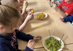 Dzieci próbują nachosów z guacamole.