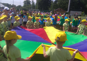 Dzieci trzymają chustę animacyjną, w środku jest 1 piłeczka, która ma wypaśc przez otwór w chuście.