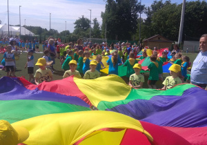 Dzieci trzymają chustę animacyjną, w środku jest 1 piłeczka, która ma wypaśc przez otwór w chuście.