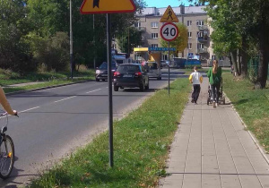 Znaki ostrzegawcze: uwaga w pobliżu szkoła, uwaga ostry zakręt w prawo, uwaga będzie przejście dla pieszych, znak zakazujący przekraczania prędkości 40 km na godzinę, w oddali znak informacyjny - przejście dla pieszych.