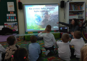 Dzieci oglądają prezentację na tablicy multimedialnej.