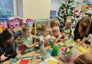 Dzieci wraz ze swoimi bliskimi osobami wykonują ozdoby świąteczne.