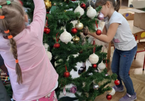 Dzieci ubierają choinkę.