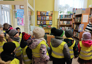 Dzieci wręczają pracownikowi Biblioteki świąteczną kartkę z bożonarodzeniowymi życzeniami i śpiewają pasorałkę.