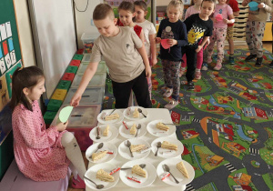 Dzieci wręczają laurki dla jubilatki oraz częstują się tortem.