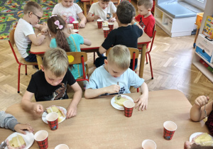 Dzieci jedzą tort urodzinowy.