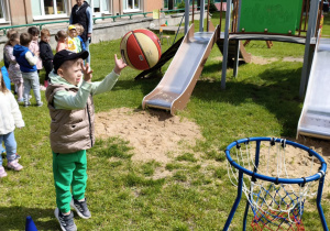 Chłopiec rzuca piłką do kosza.