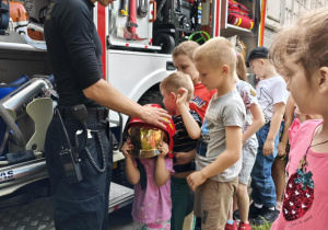 Chętne dzieci przymierzają kask strażacki.