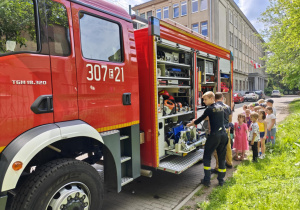 Dzieci oglądają wyposażenie wozu strażackiego.