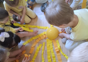 Dzieci układają słońce z pasków bibuły.