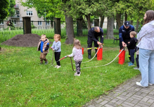 Dzieci korzystają ze sprzętu strażackiego.