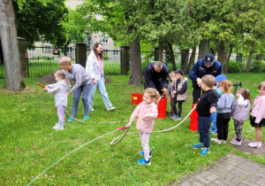 Dzieci korzystają ze sprzętu strażackiego.